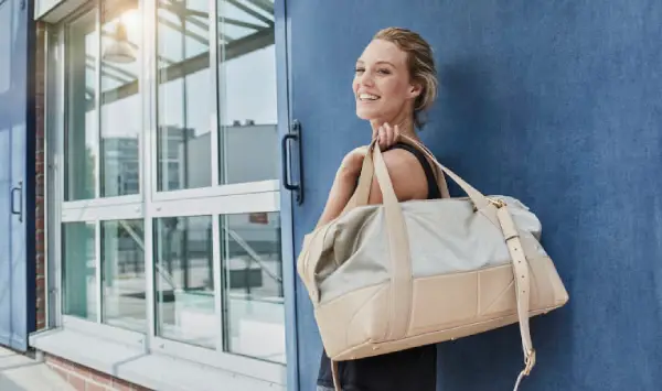 A woman holds a travel duffle bag