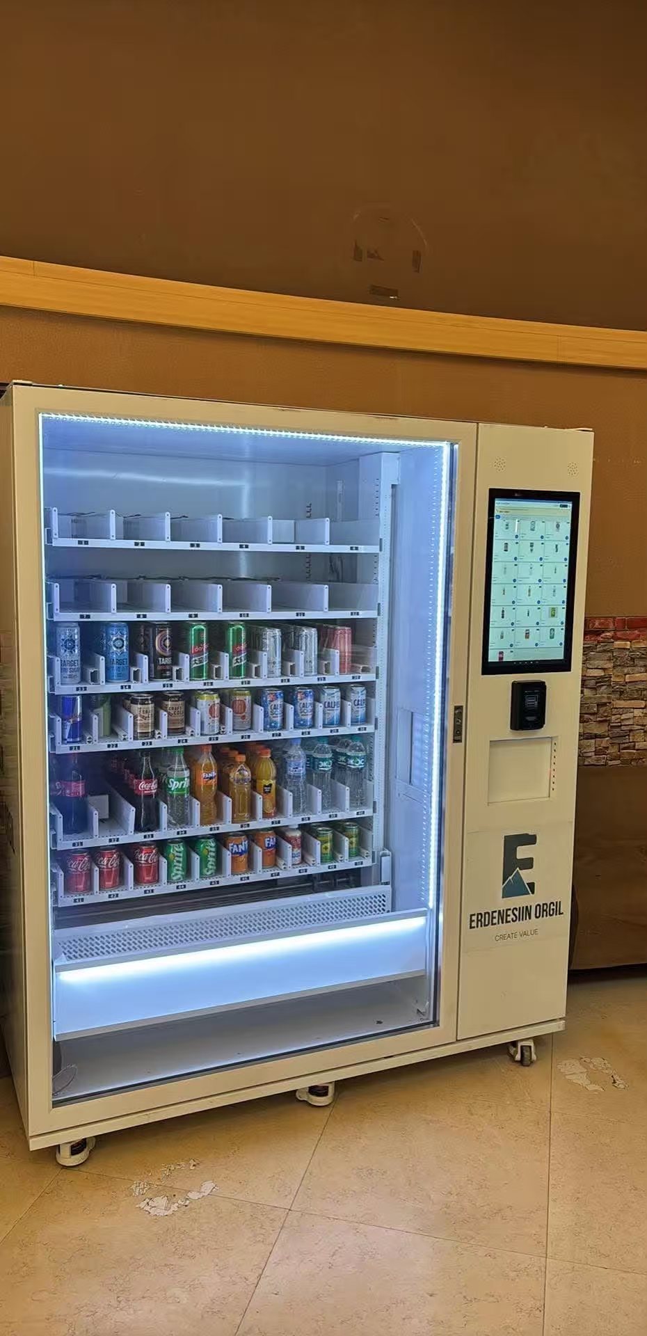 High-capacity elevator drink vending machine dispensing cold bottled beverages near a Mongolian airport terminal concourse