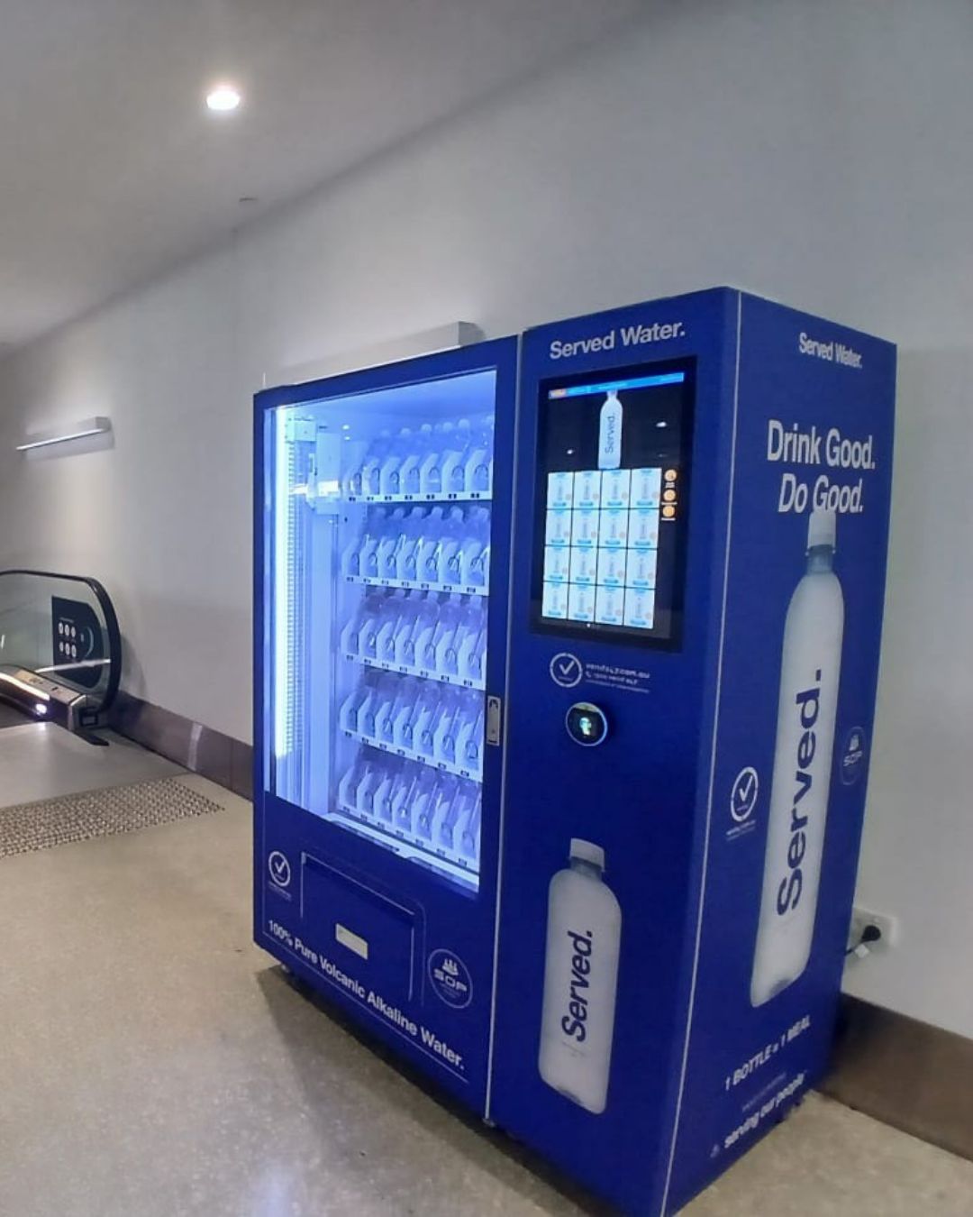 High-capacity refrigerated drink vending machine dispensing bottled water in an Australian train station concourse