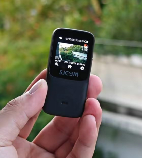 An SJCAM C200 Pro Action Camera Held with a Person's Fingers