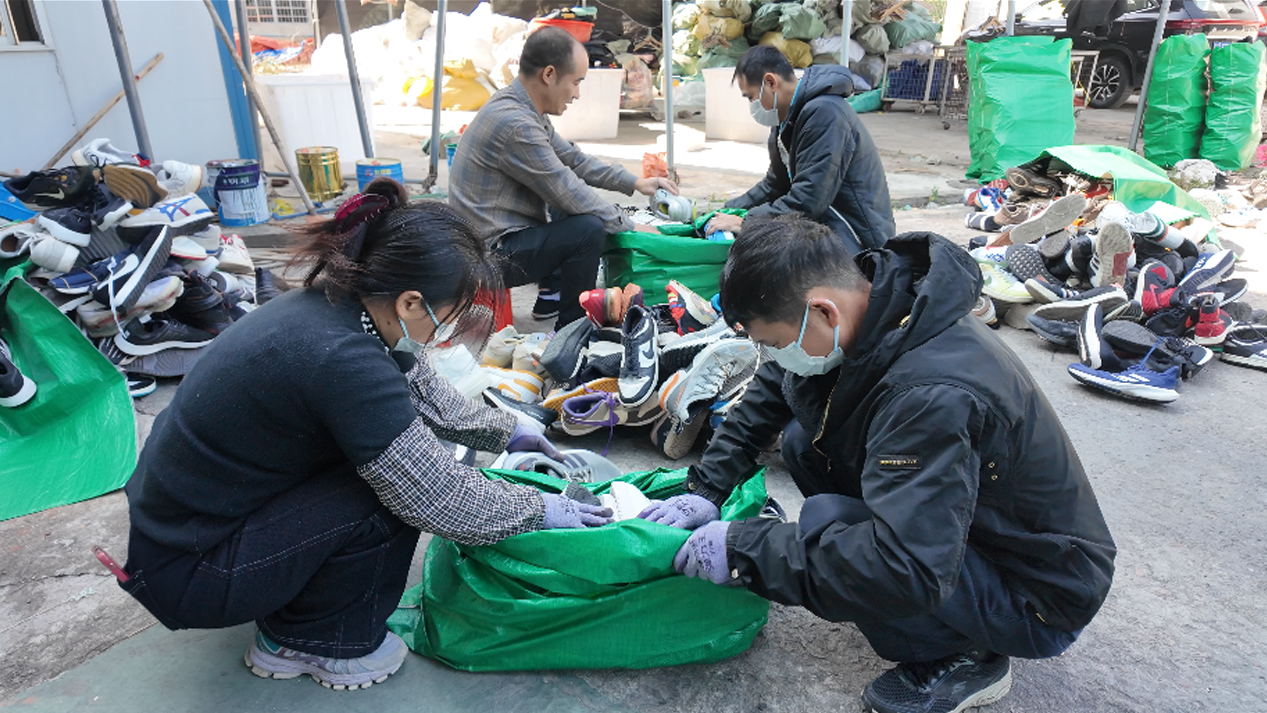Quality inspector checking soles of used branded shoes for wear and tread integrity