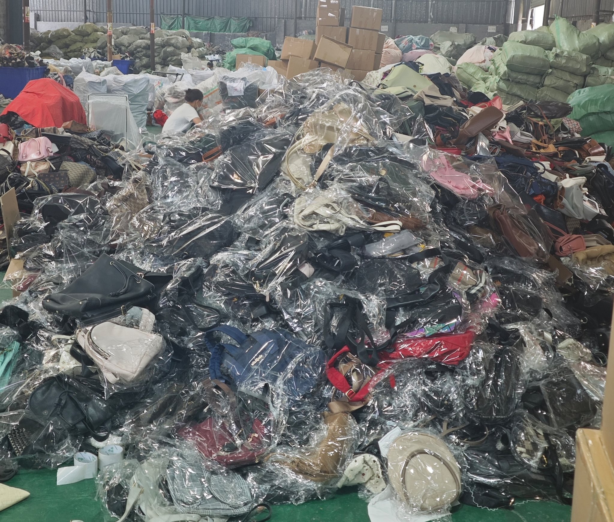 Bulk stock of sorted Grade A used fashion bags in a China wholesale factory