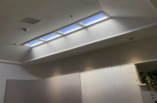 Luz de techo empotrada con haz solar inclinado Lumin instalada al ras en salón de lujo creando luz solar cálida y sombras naturales