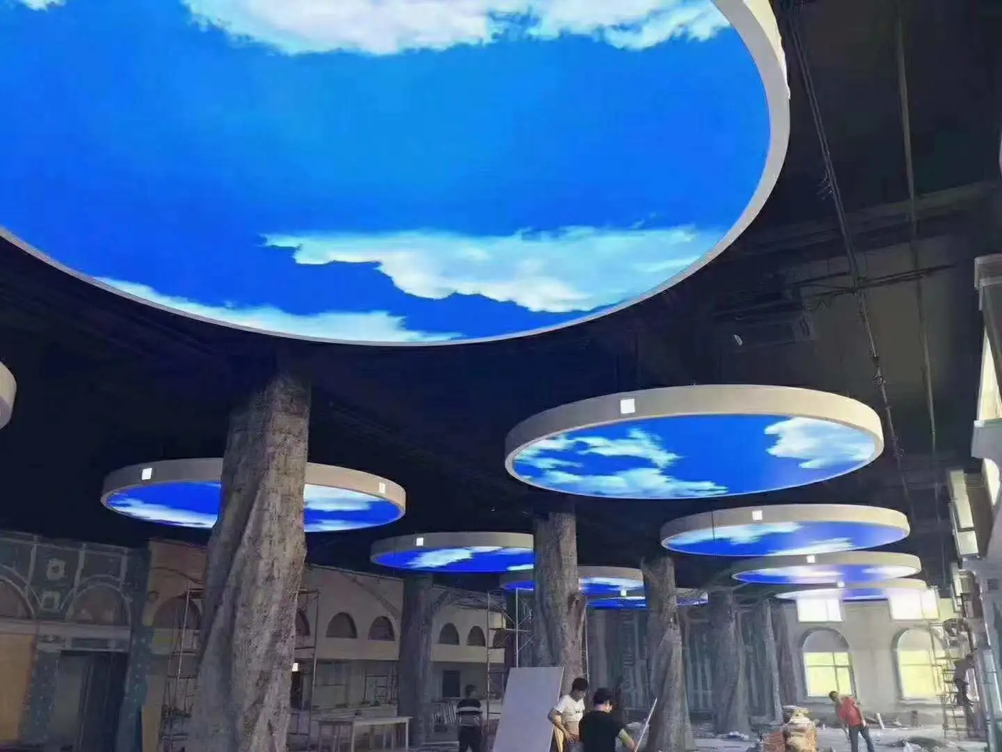 Lumin circular LED skylight panel above dining table in restaurant with blue sky motif