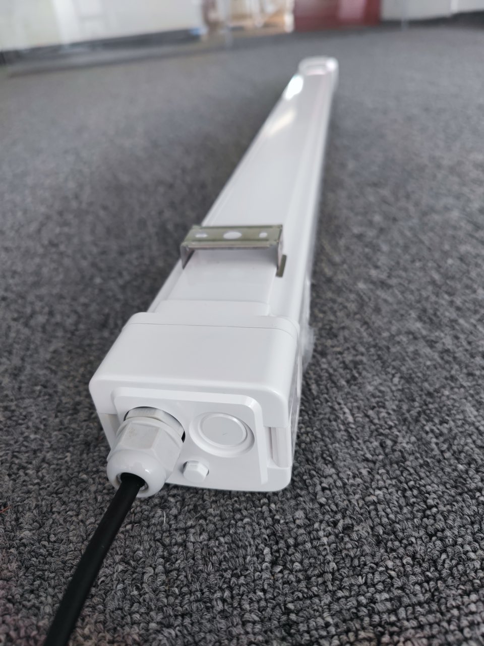 Side angle view of Lumin tri-proof light showing snap-fit end cap with breather valve and silicone gasket seal for IP65 waterproof and dustproof protection.