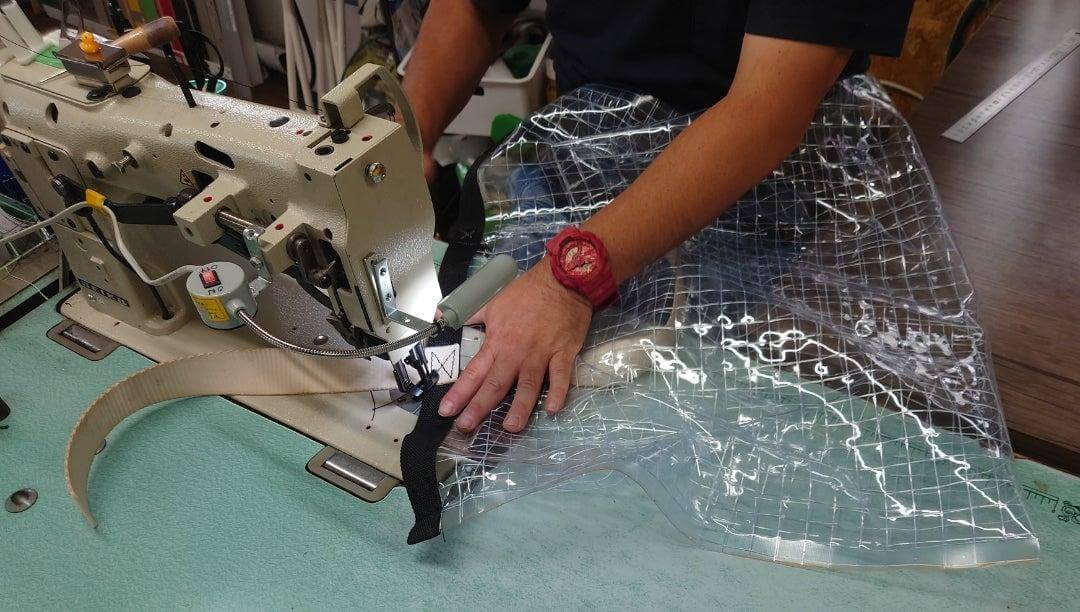 専門工場で、工業用ミシンがPUバッグとPVCバッグの素材サンプルを縫製している様子をクローズアップで撮影した写真。