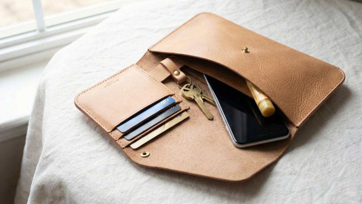 An open clutches bag with a smartphone and neatly organized everyday essentials.