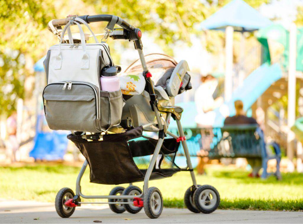 A parent pushing a stroller with a baby bag and diapers packed for convenient, organized outings.