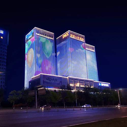 High-rise building facade illuminated with vertical multicolor lights at night