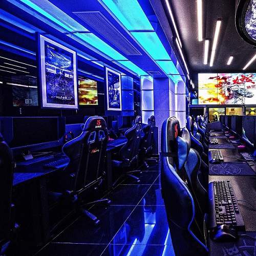 Gaming cafe with blue ceiling lighting and illuminated computer stations