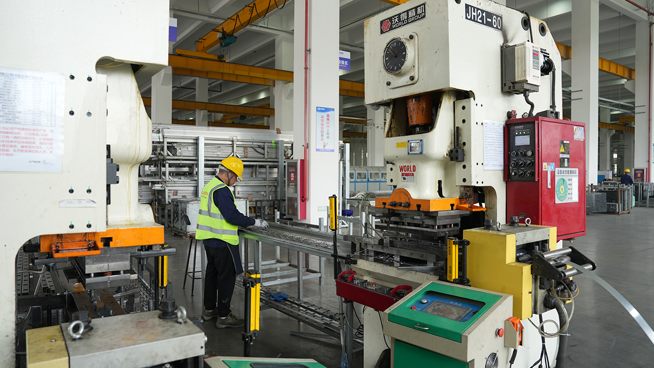 ALLWORTH factory worker handling long metal components among production machines