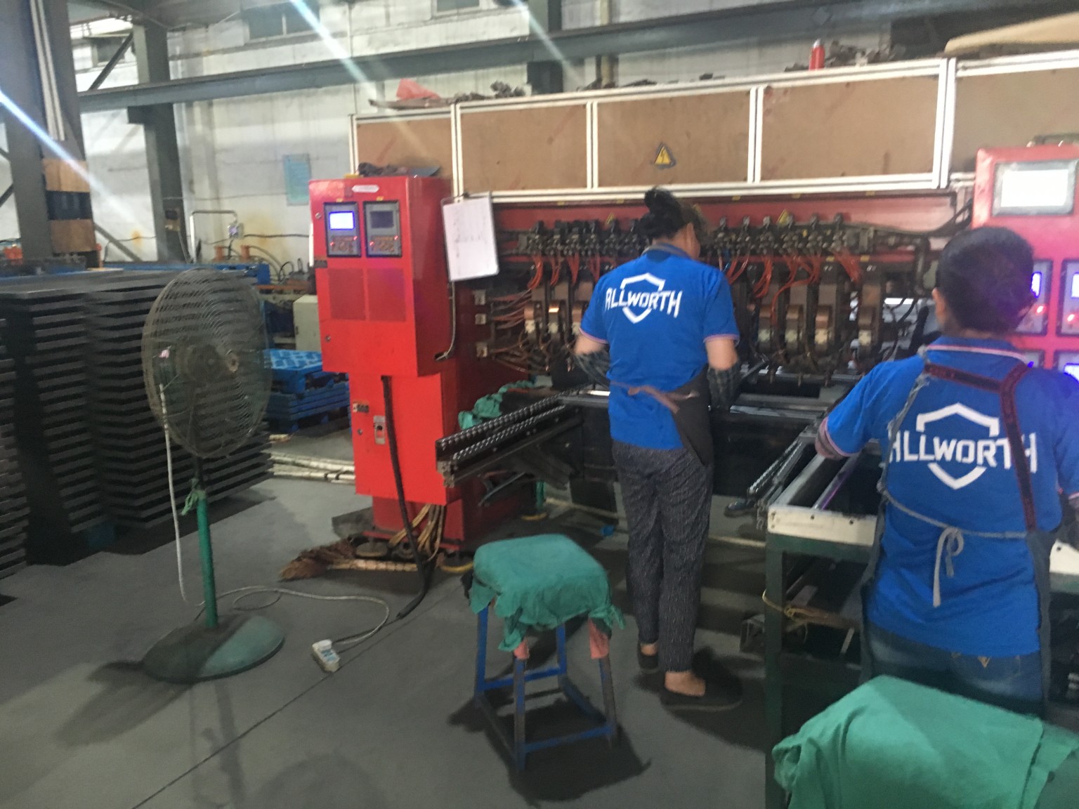 ALLWORTH workers handling metal components at a workshop production station