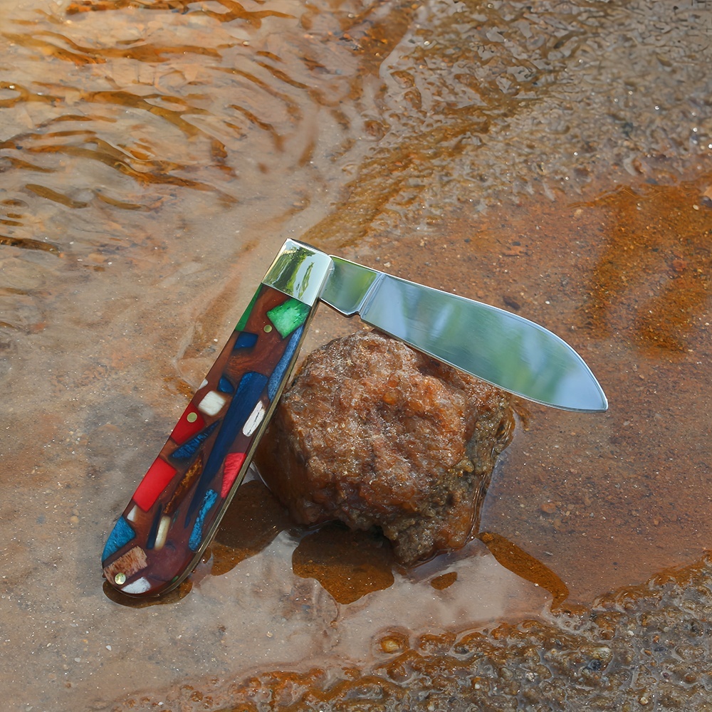 folding edc knife leaning against a small stone