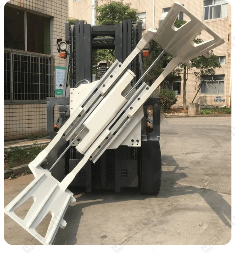 Bale clamp for forklift gripping a large, irregular-shaped bale of recycled cardboard, emphasizing its compression capability.