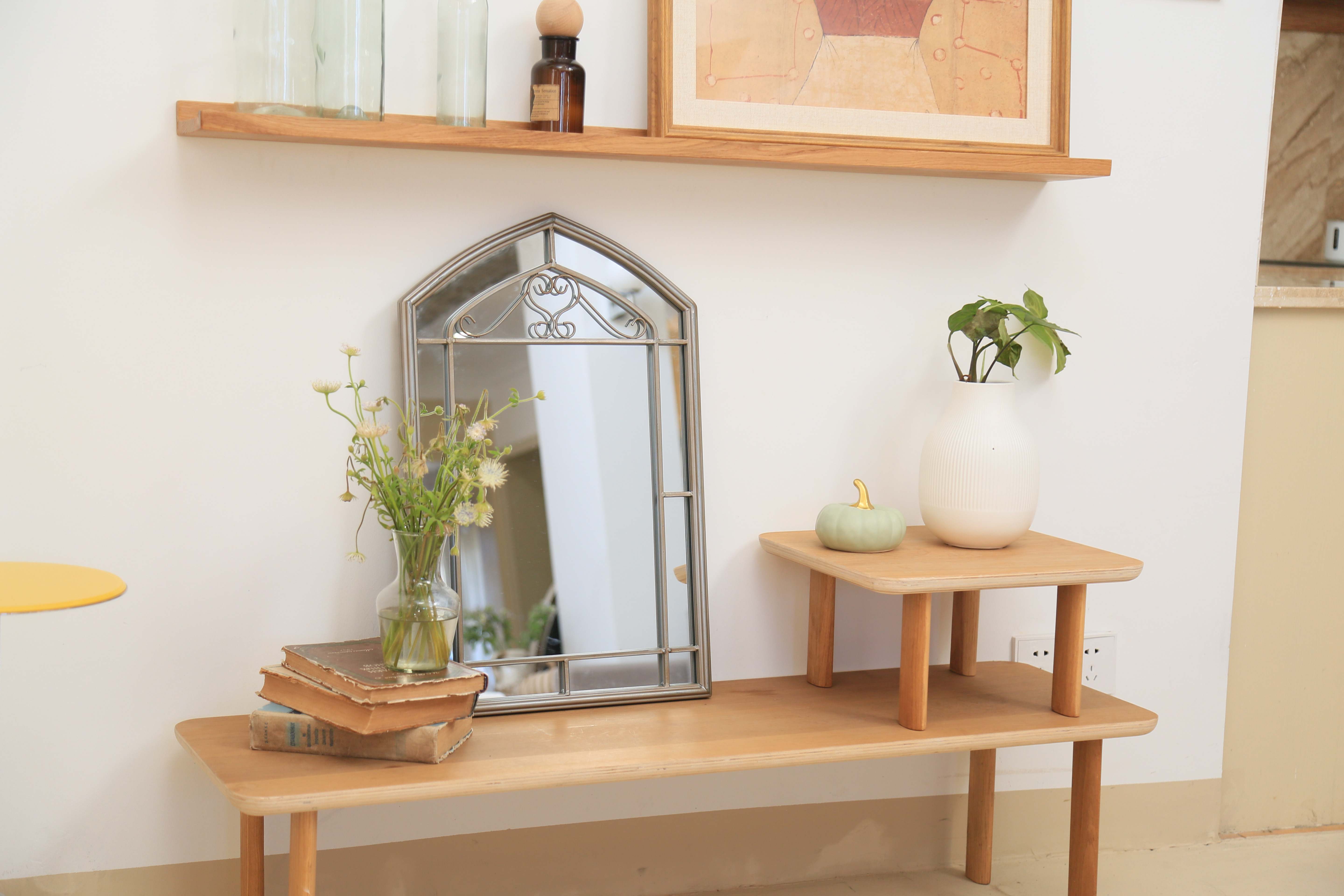 Metal frame mirror in above a table beside plants