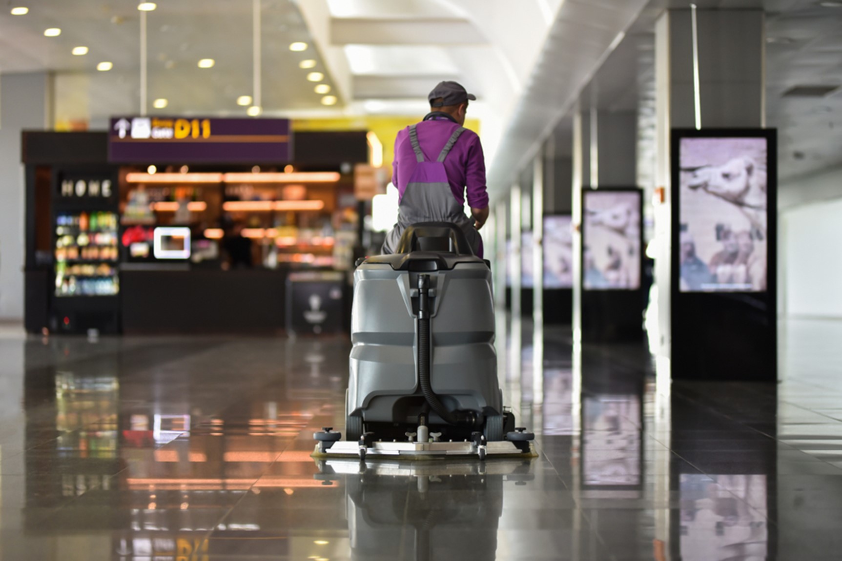 A man riding a ride on floor cleaner from an airport terminal