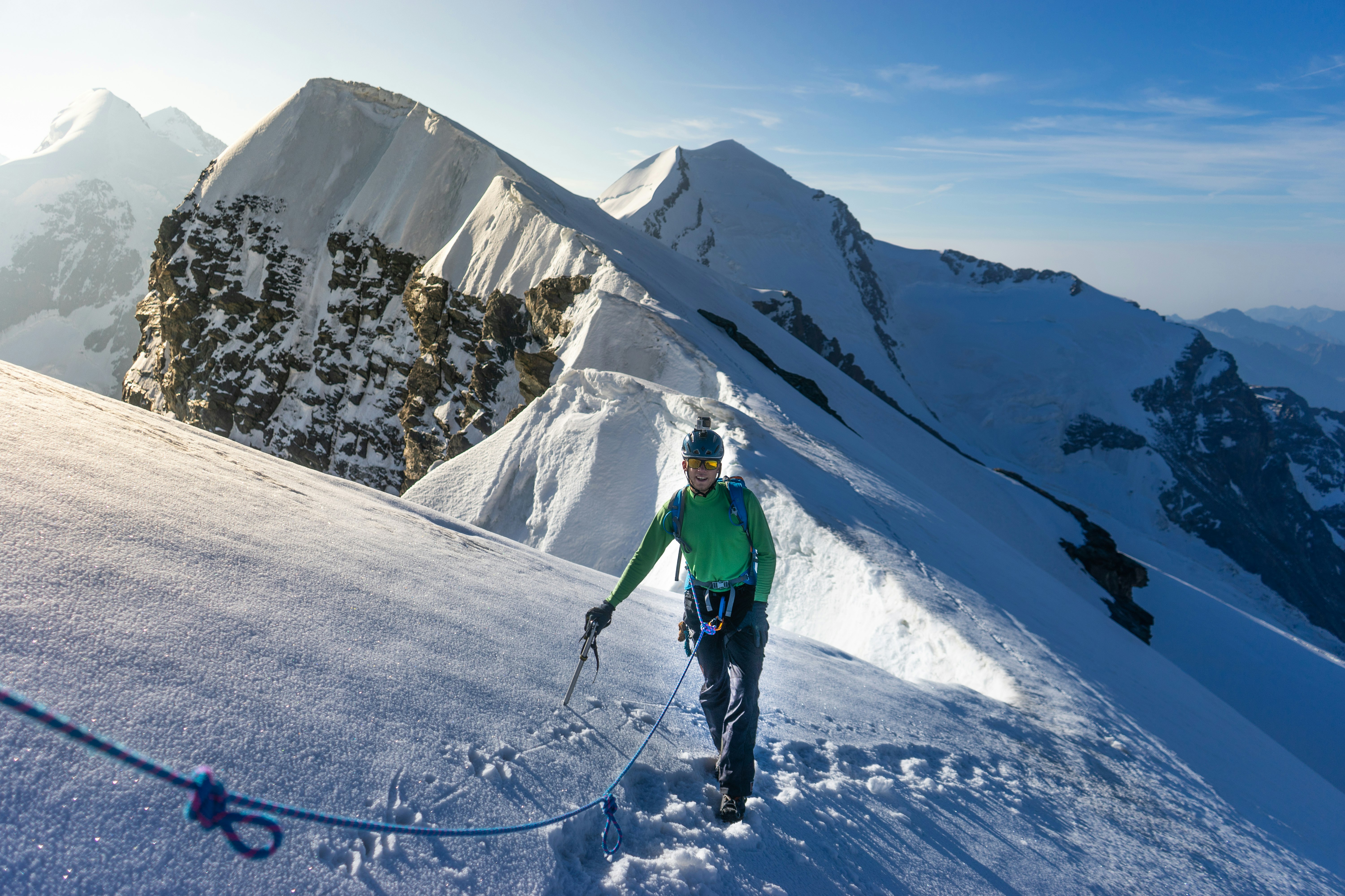 mountain guide and client heading up a glacier towards a high alpine summit on a beautiful summer morning in the French Alps