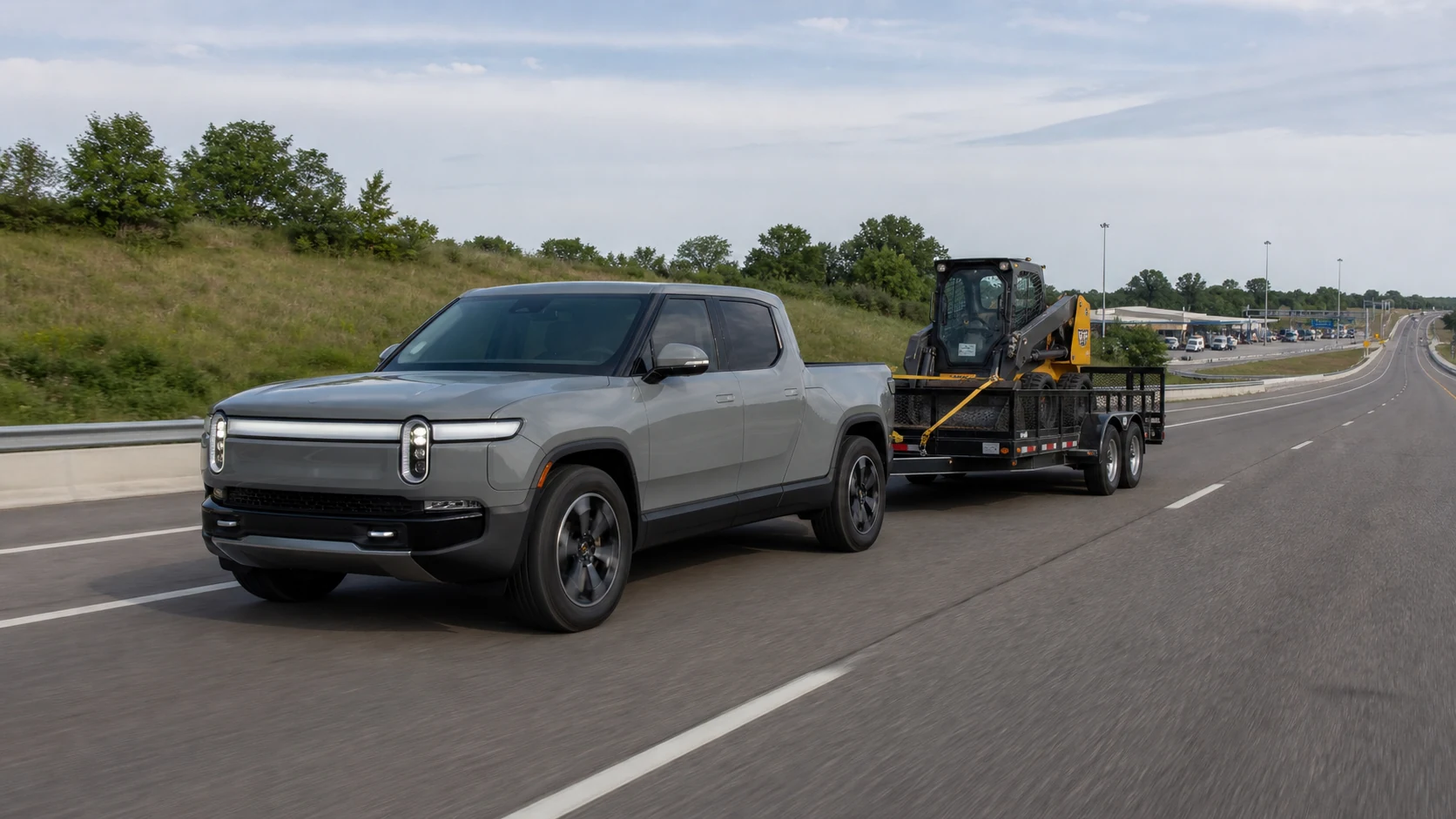 Electric pickup towing a loaded tandem-axle utility trailer on a divided highway