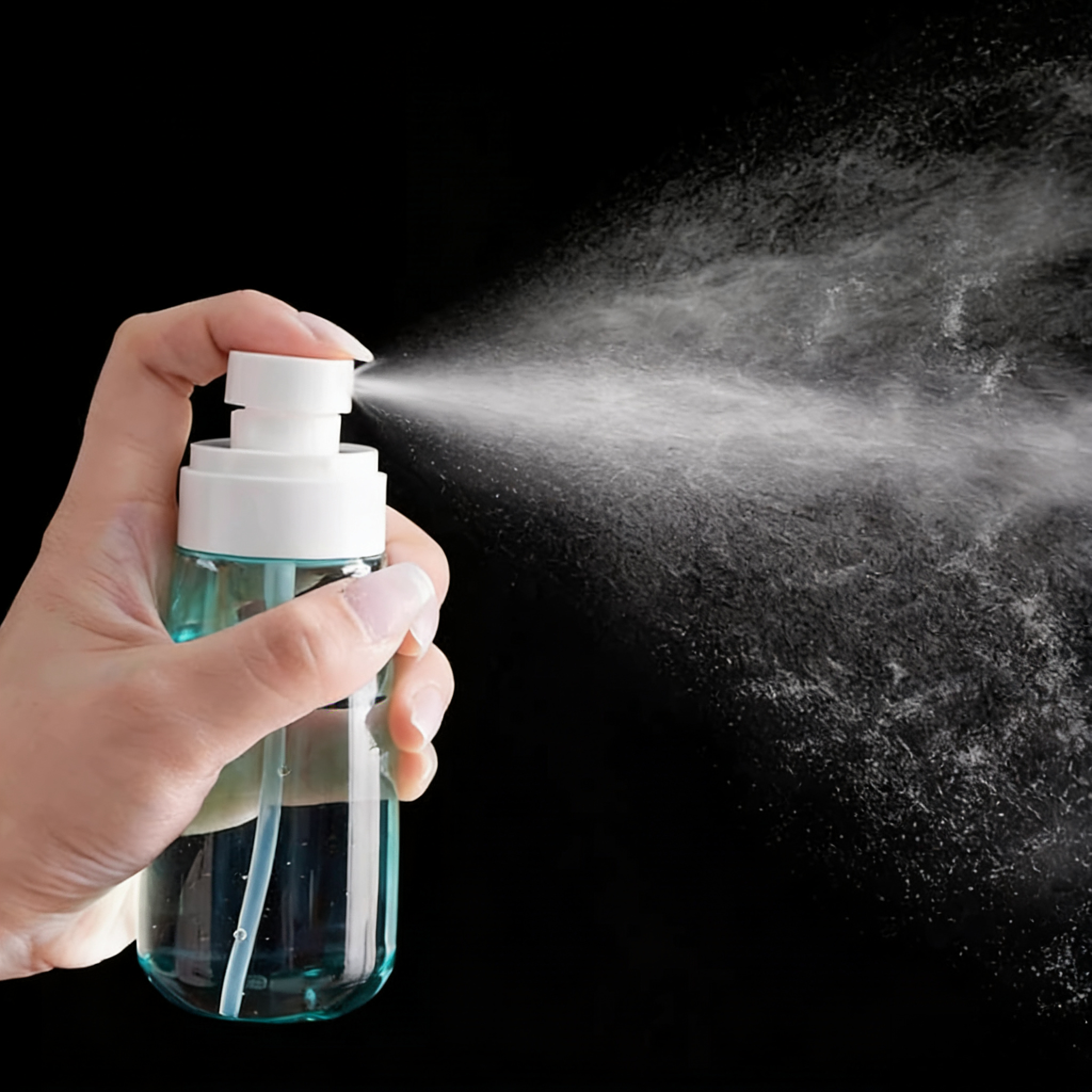 Hand pressing a blue fine mist spray bottle, releasing a visible ultra-fine mist against a black background