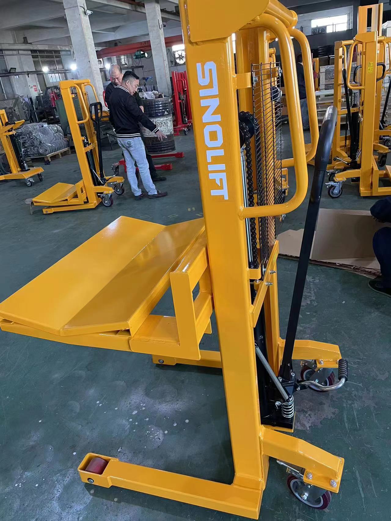 Hard chrome-plated manual hydraulic stacker PFV6150 lifting a heavy flexible packaging roll to 1500mm height with precision and stability.
