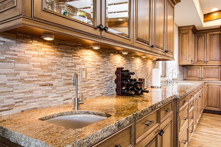 Modern grey kitchen with a pull-down kitchen faucet over a stone countertop