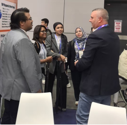 Group of people having a discussion at the OGA exhibition