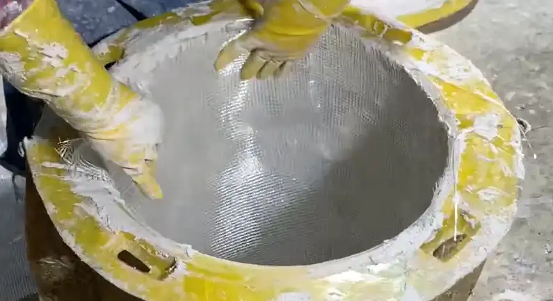 Worker applying reinforced composite material inside a round planter mold at the Ronglin factory