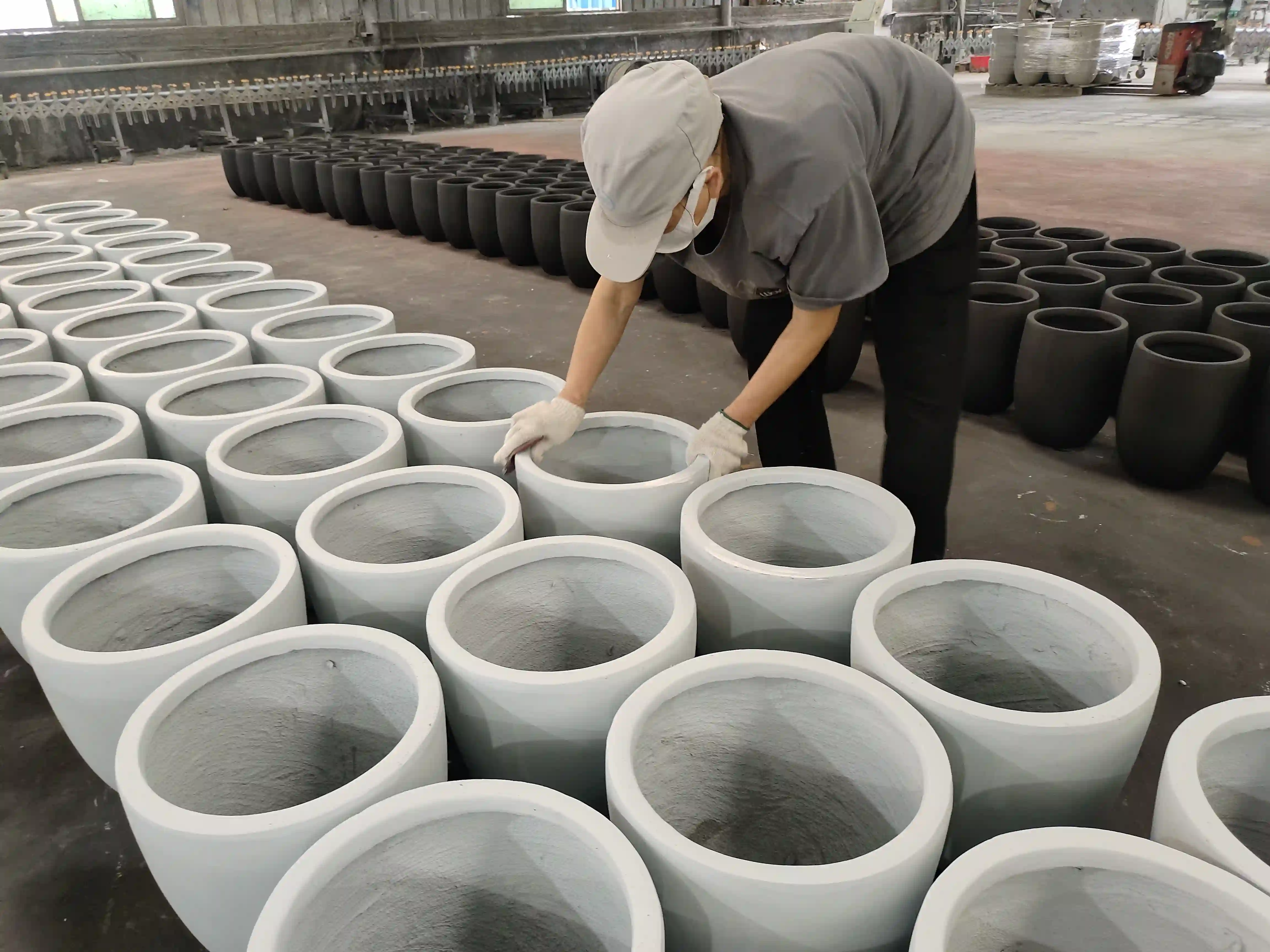 Worker checking surface consistency across a batch of round planters at the Ronglin factory