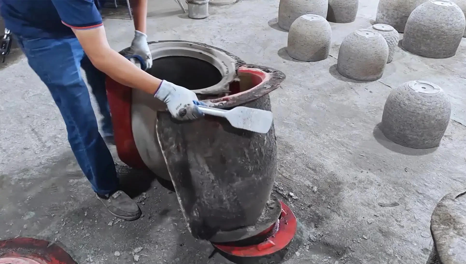 Worker preparing the rim and exterior of a round planter during factory production