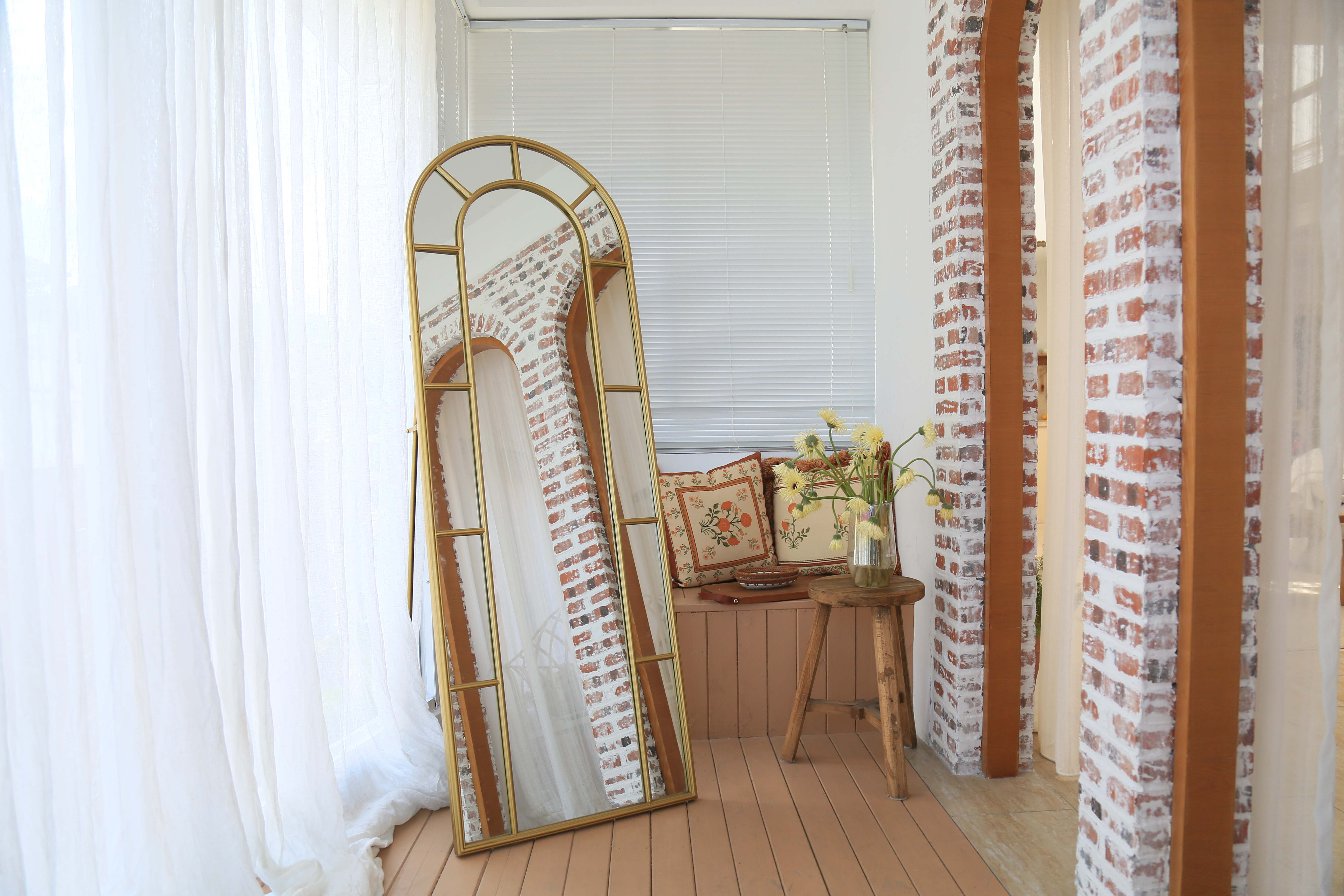 gold full length mirror standing at the corner of a livingroom