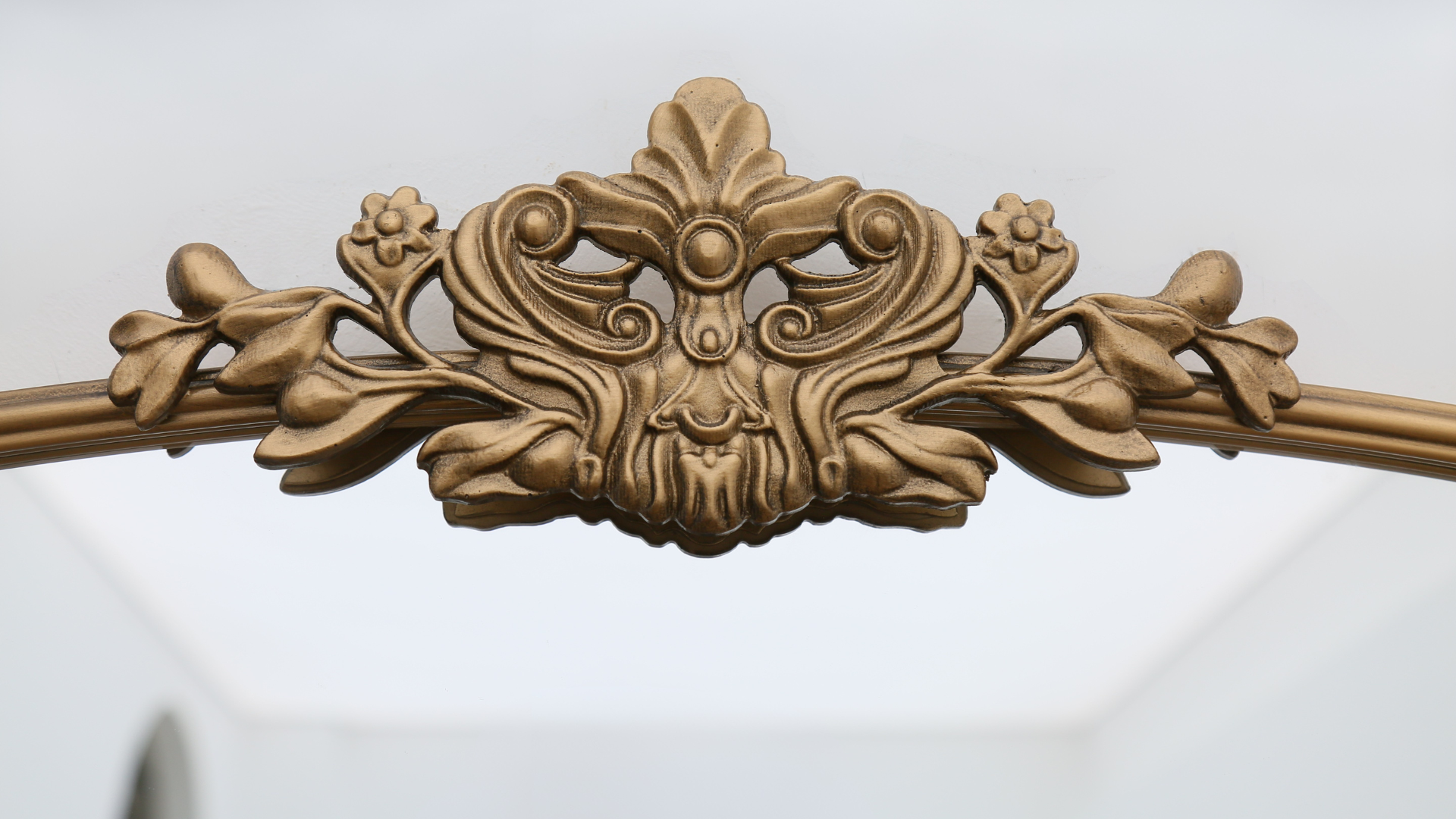 Baroque Sleek Floral Gold Frame Ornate Mirror reflecting natural light in a factory setting with close up detailed view