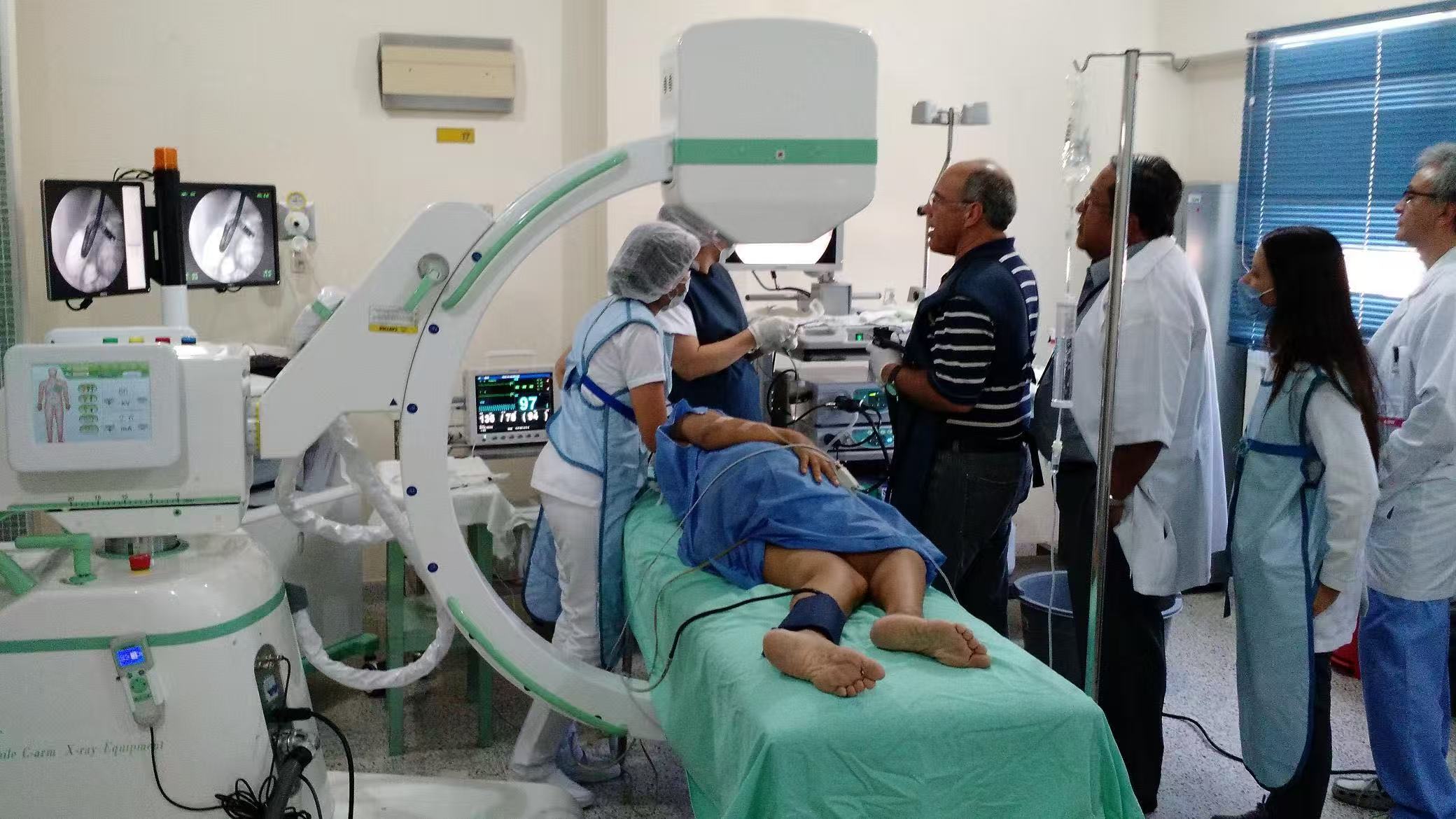 the doctor is using the c arm fluoroscopy machine.