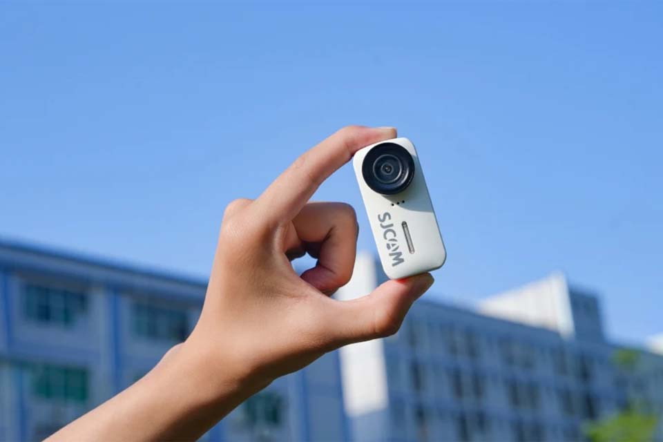 A Person Holds the SJCAM C110 Plus Action Camera between Two Fingers