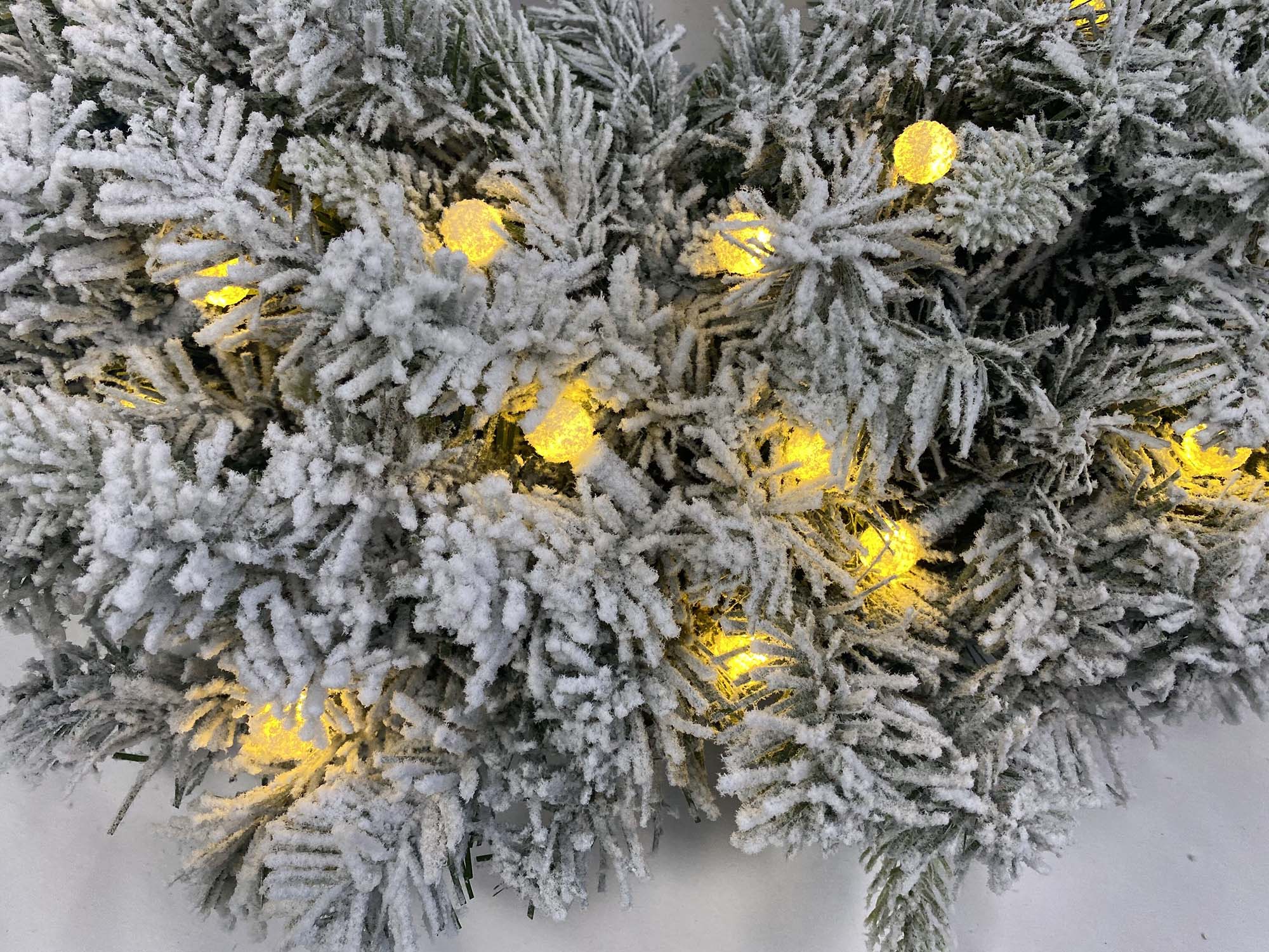 Pre lit flocked Christmas wreath with warm white LED lights and snow covered pine needles. This artificial winter wreath adds cozy festive charm to front doors, mantels, and indoor holiday decorations