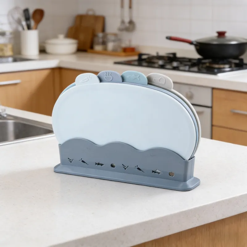 4-piece color-coded cutting board set with food icons (vegetable, hot food, fish, meat) and a storage rack, displayed on a kitchen countertop in a modern kitchen with stove and sink.