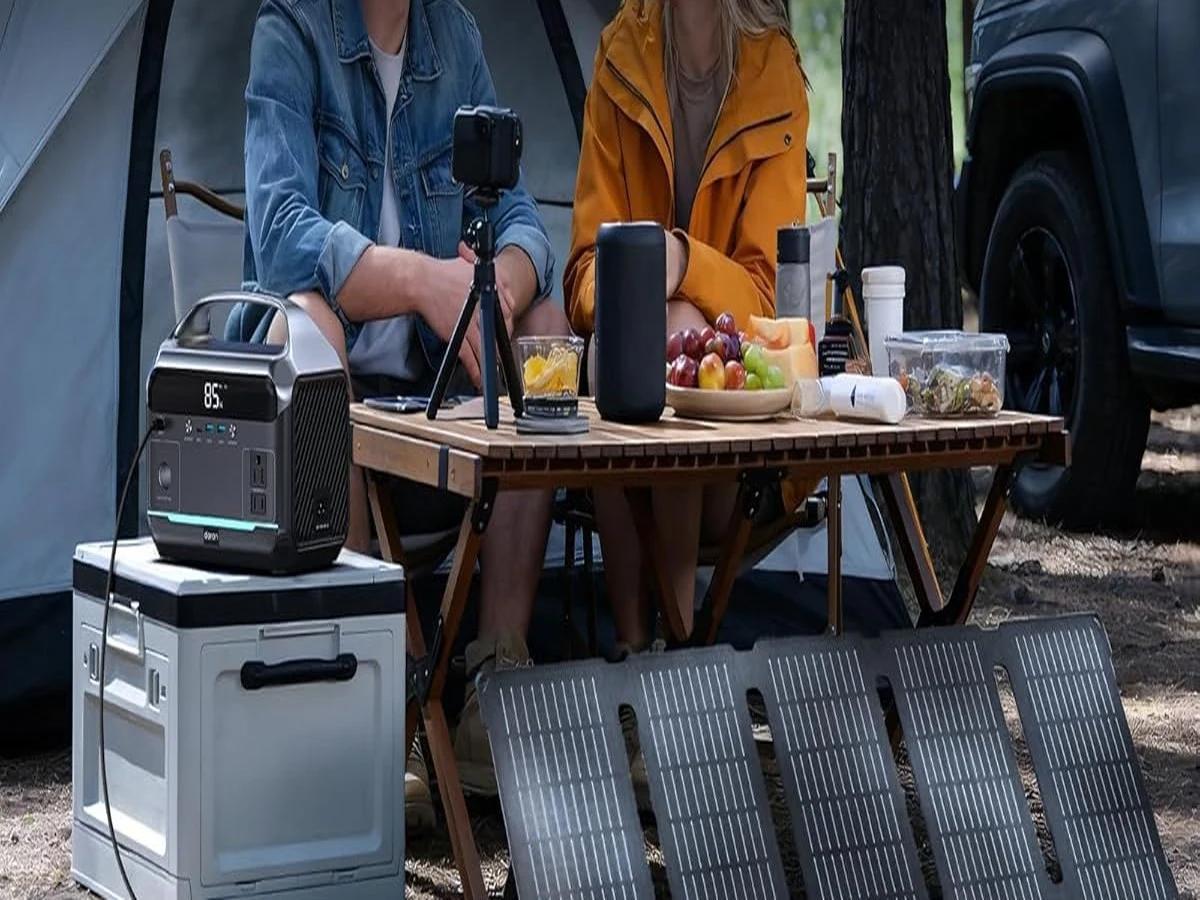 Campers at a picnic table running camera and phone charging gear from a portable power station