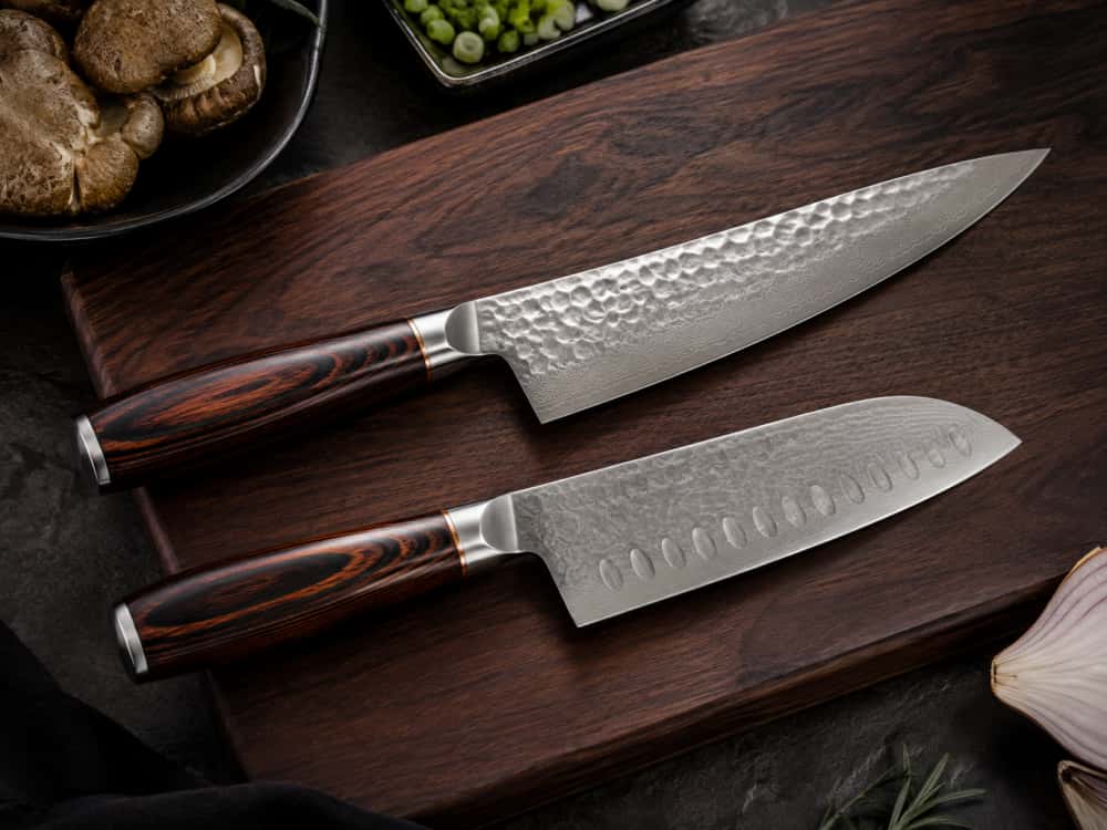 Japanese-style chef knife and Santoku knife with premium pakkawood handles on a dark wooden cutting board, featuring detailed textured blades.