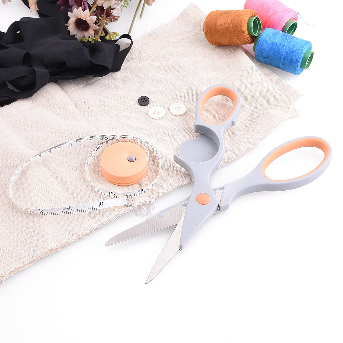Grey and orange ergonomic sewing scissors set with measuring tape, thread spools and buttons, DIY craft and tailoring tools