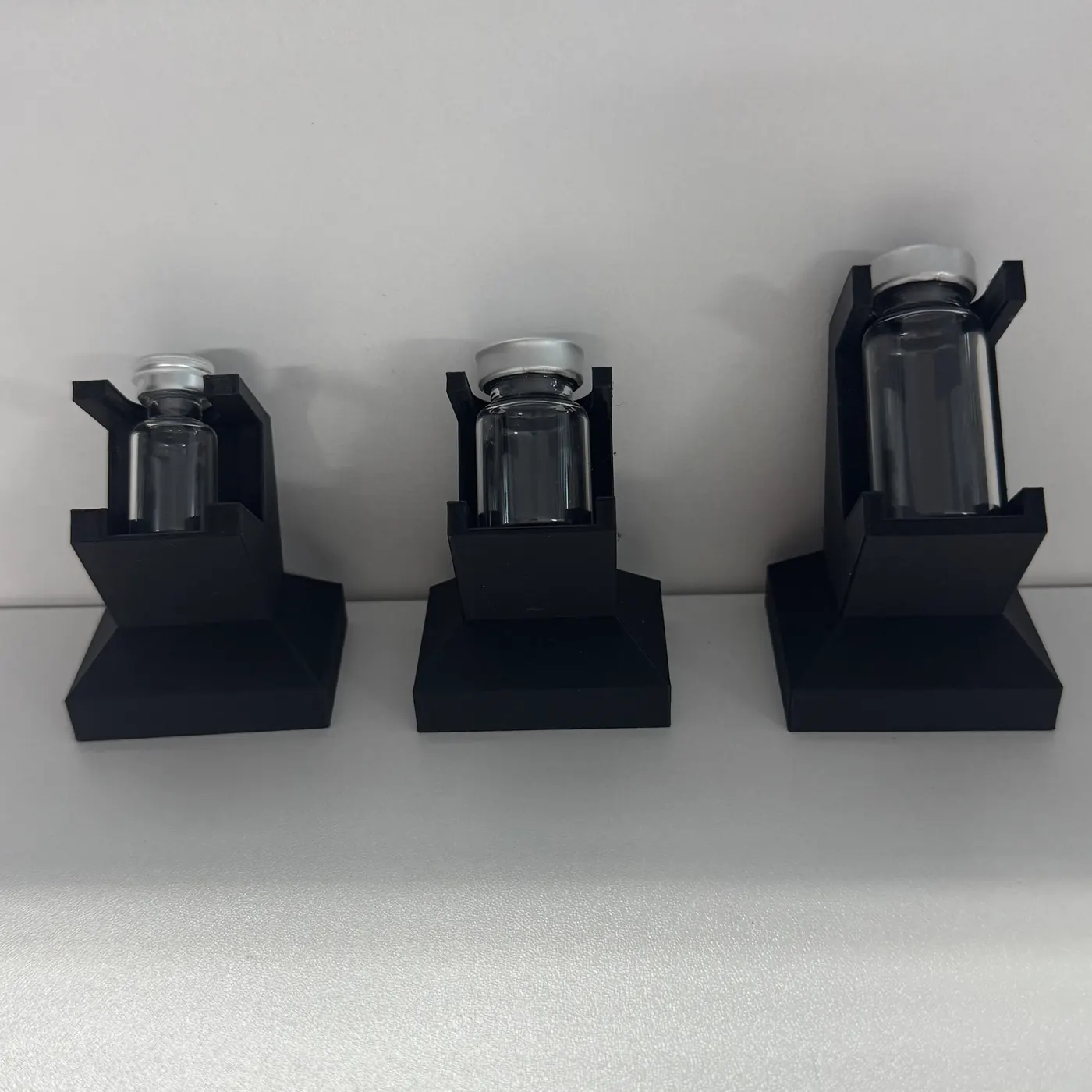 three vial display stands in a line-up against a wall, vials loaded