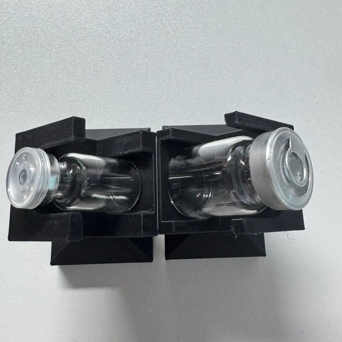 top view of a 3 ml vial (16 mm body) beside a 5 ml vial (22 mm body) in their stands — the diameter difference
