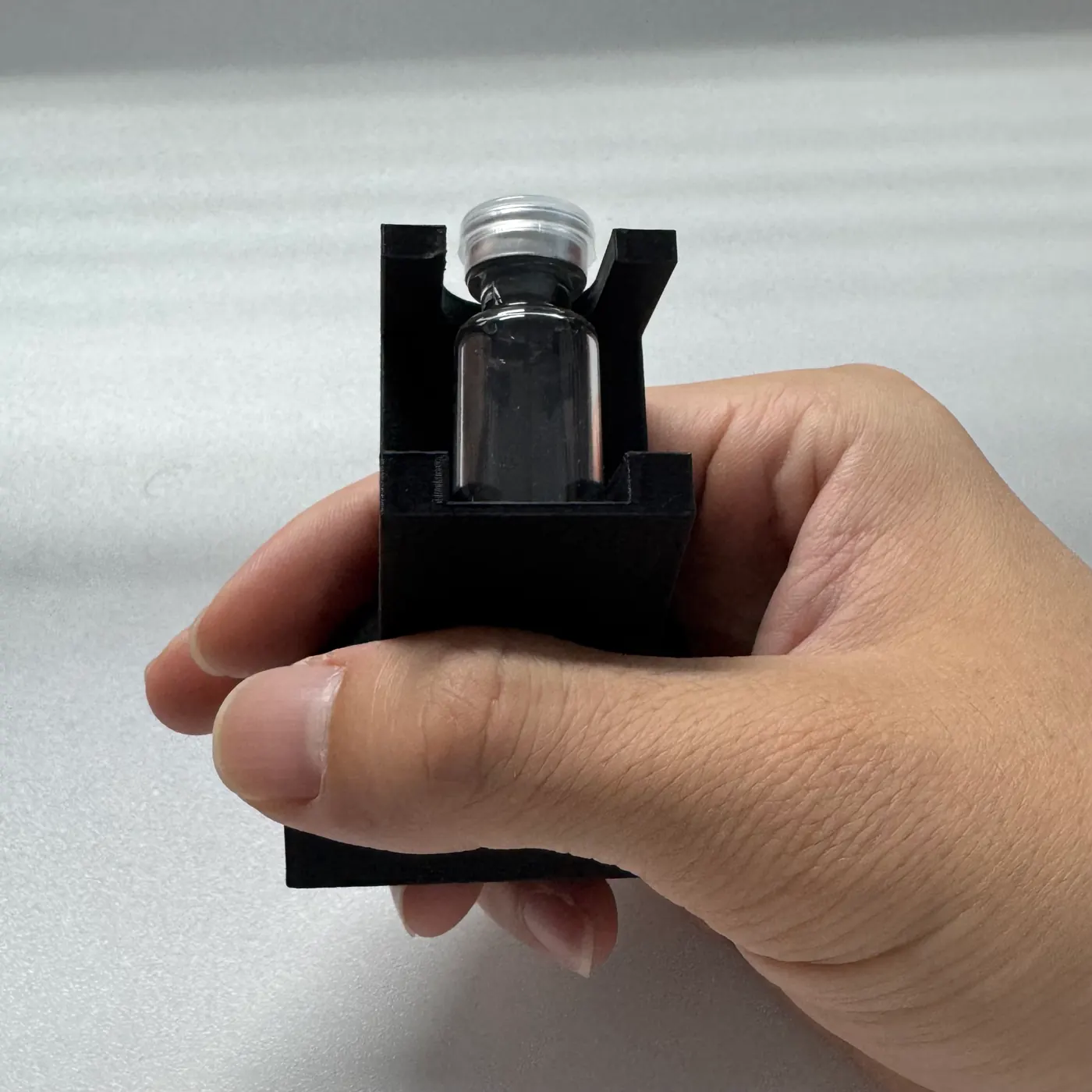 a hand holding the vial display stand to show its size