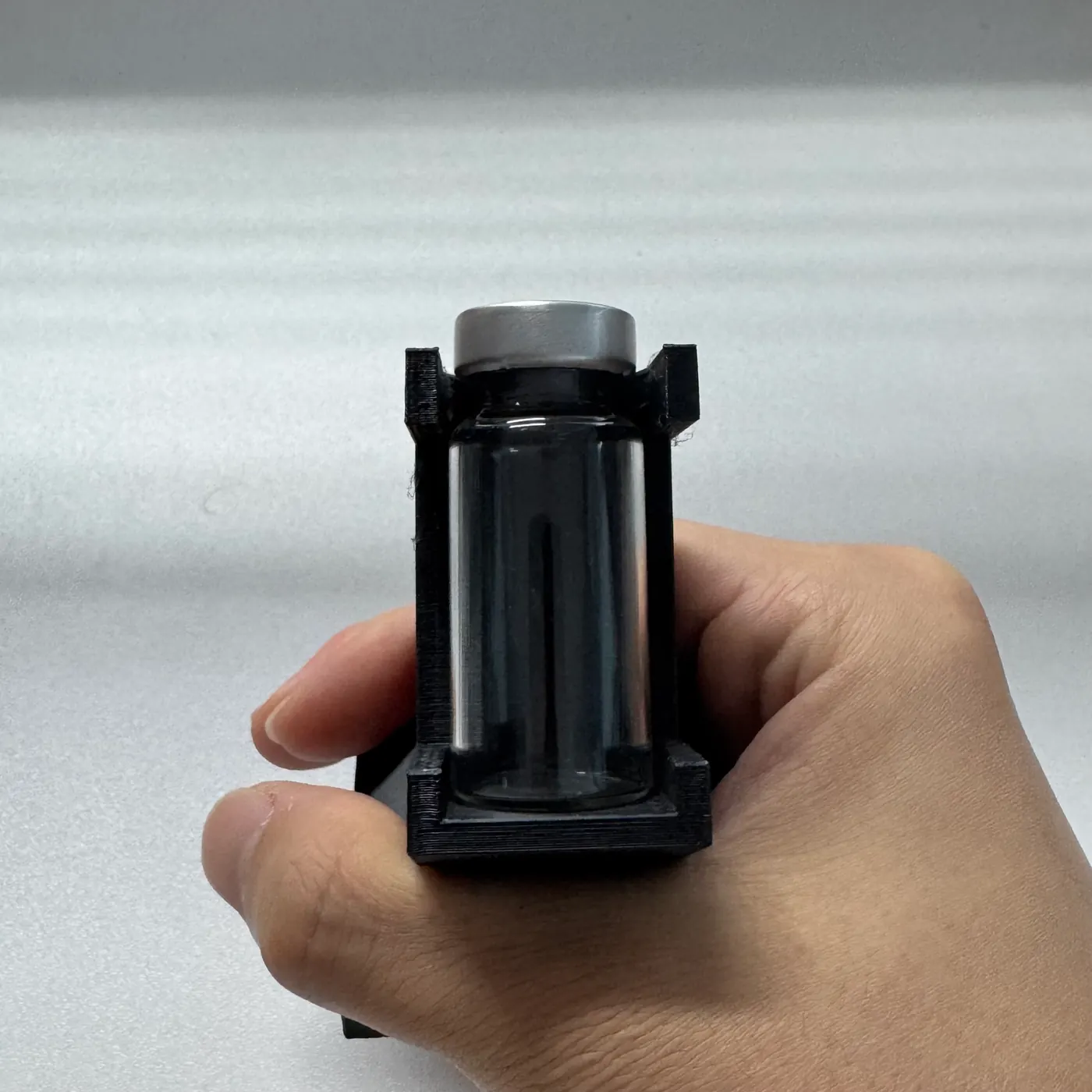 the PETG vial display stand held at an angle with a vial in place