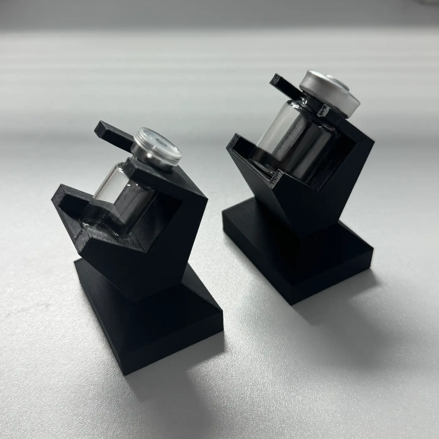 two matte black vial display stands photographed at an angle