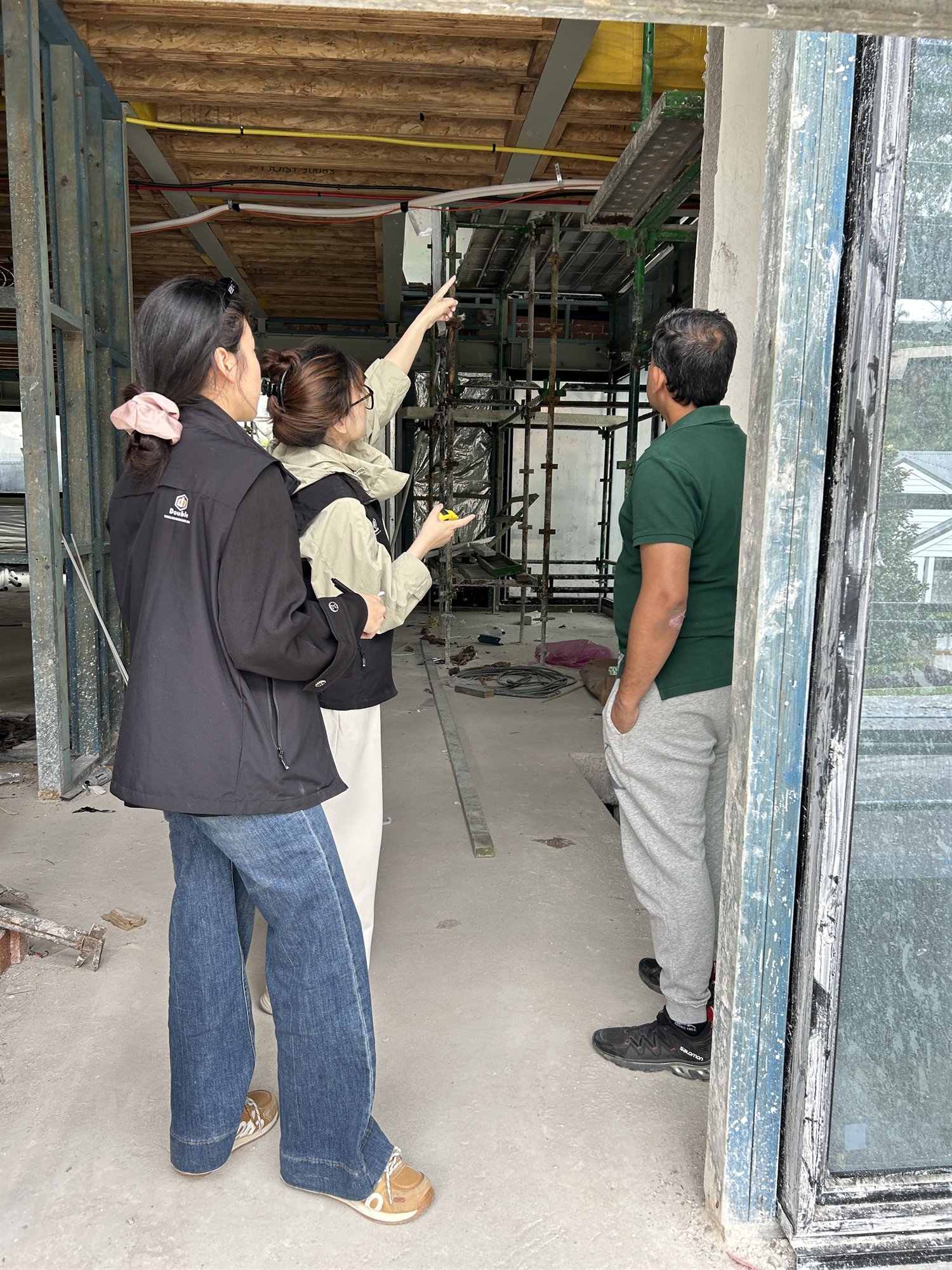 Staff and a contact discussing a stair opening at a steel-and-timber frame in a Sydney house under construction