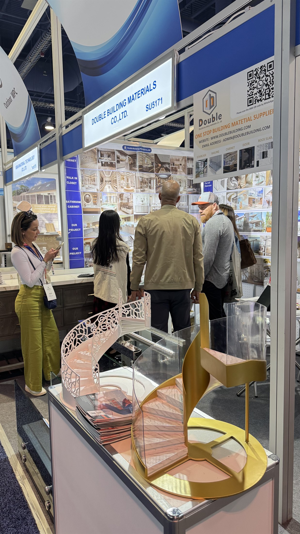 Two spiral staircase models on the counter at booth SU5171, one white ornate and one gold with glass