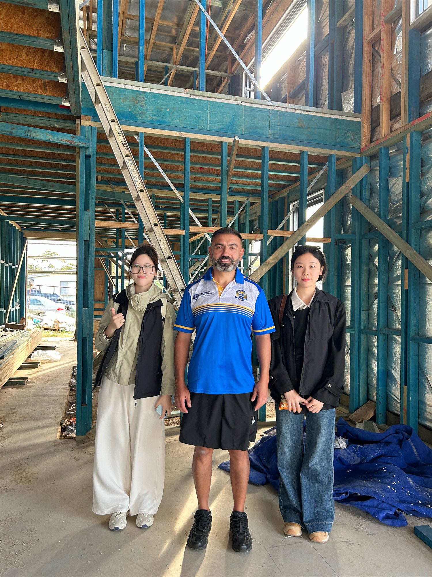 Staff standing with a contact inside a Sydney house still in blue framing