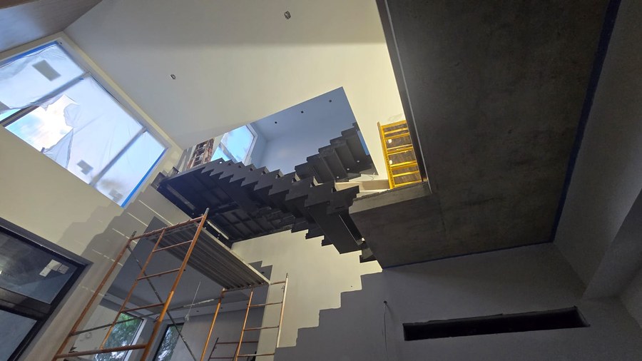 Dark steel zigzag staircase structure installed in an unfinished Florida stairwell