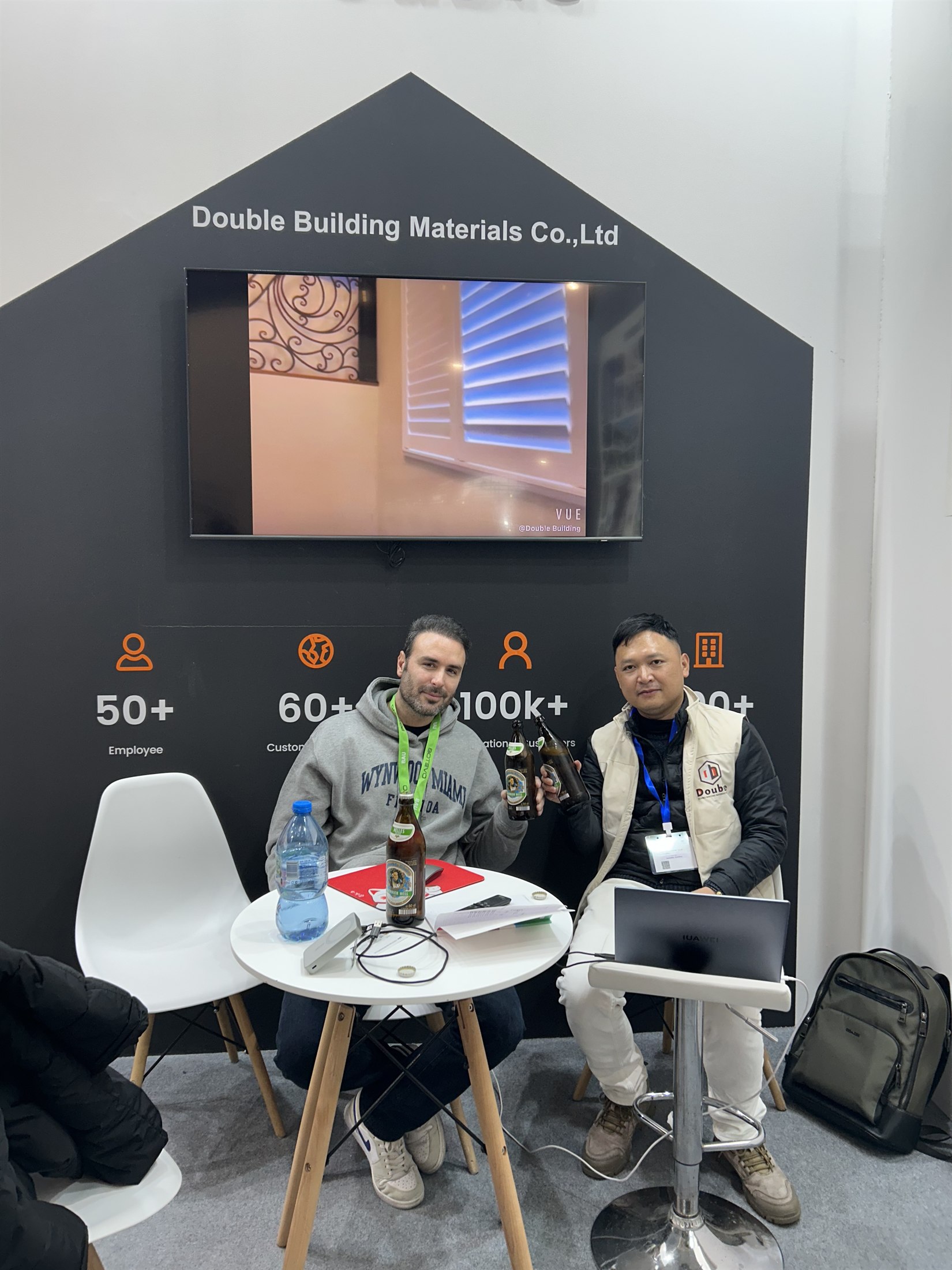 Staff and a visitor seated at a round table with a laptop on the Double Building stand