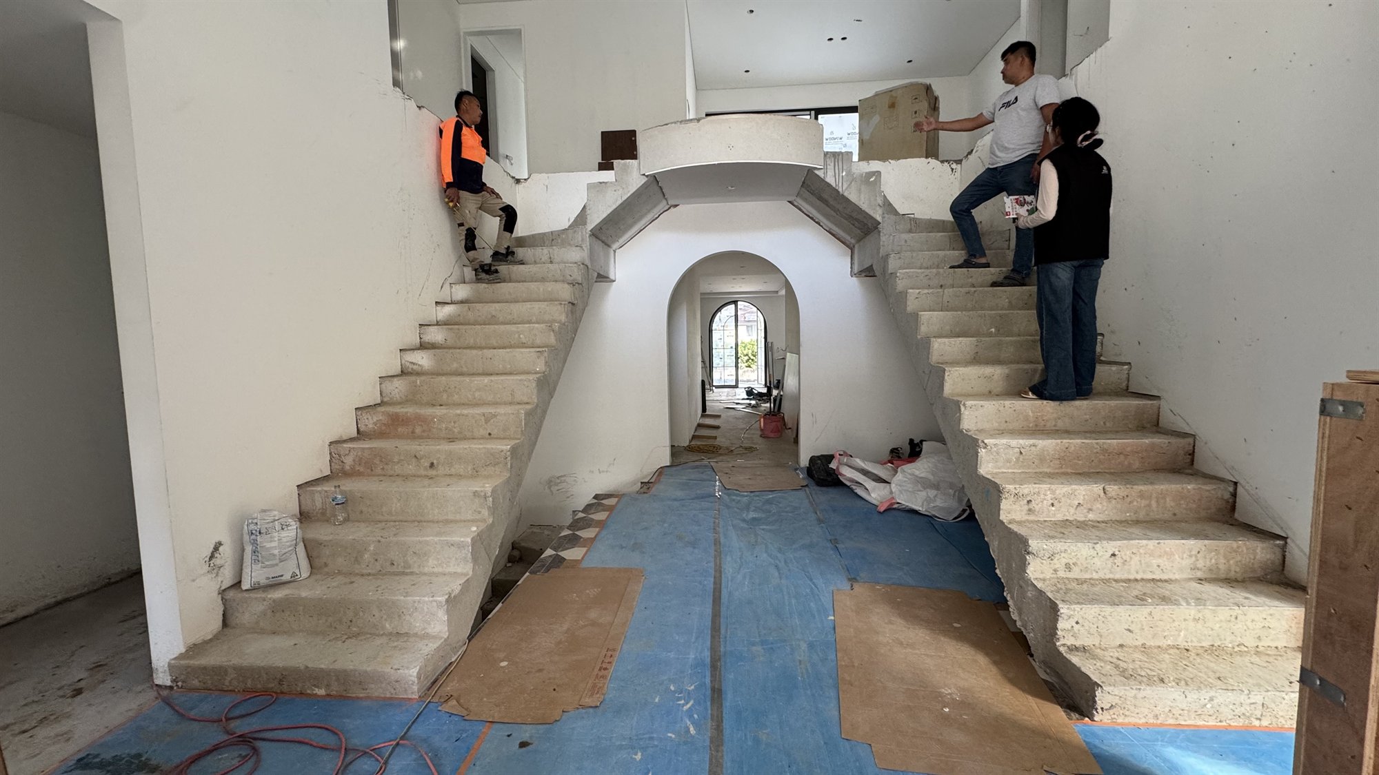 Twin unfinished concrete staircases flanking an arched opening in a Sydney home under construction