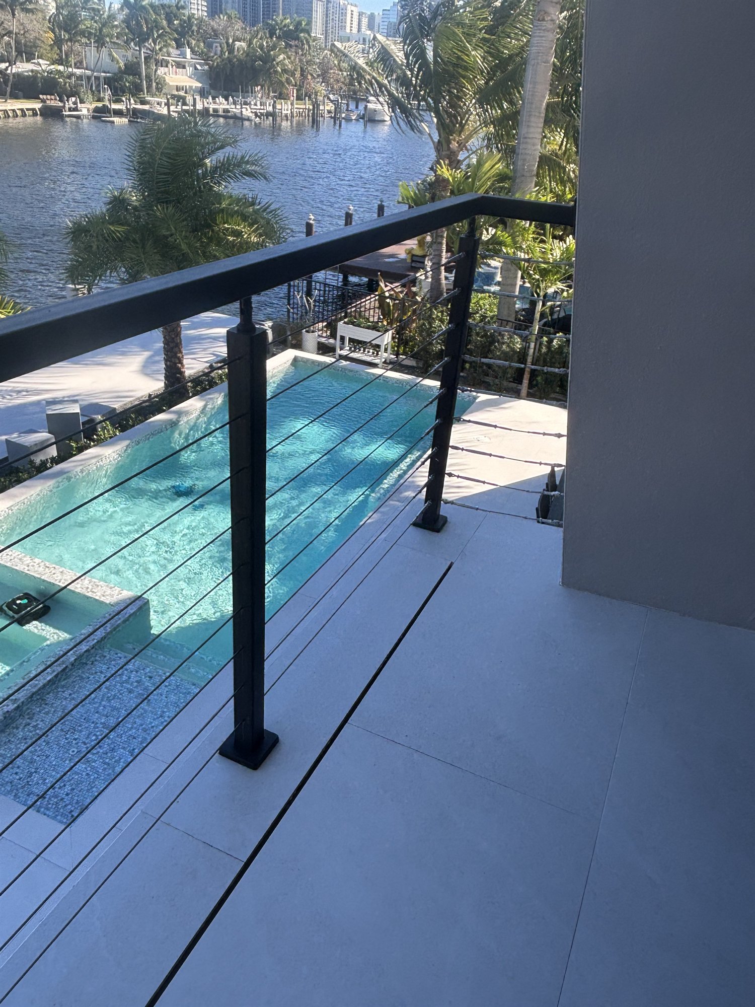 Black cable railing on a balcony overlooking a pool and canal